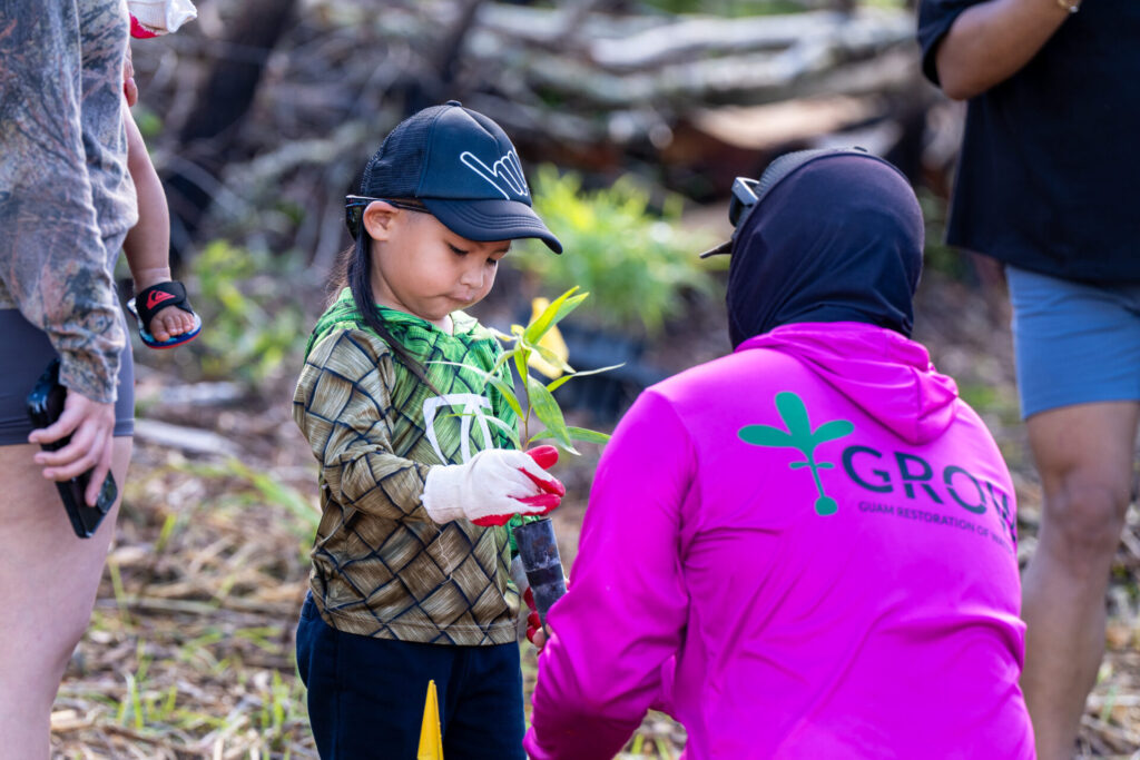 GROW Project Lead Joshua Muna assists 4-year-old Keith Daniel Santos at the GROW in Malojloj tree-planting event.  Santos was one of the many volunteers on hand that helped plant over 1200 trees at the first event of the season. 