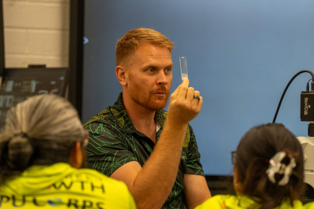 Brett Taylor, Ph.D. from the UOG CIS & Sea Grant's Fisheries Division, demonstrates how to view otoliths through a microscope to determine a fish's age.