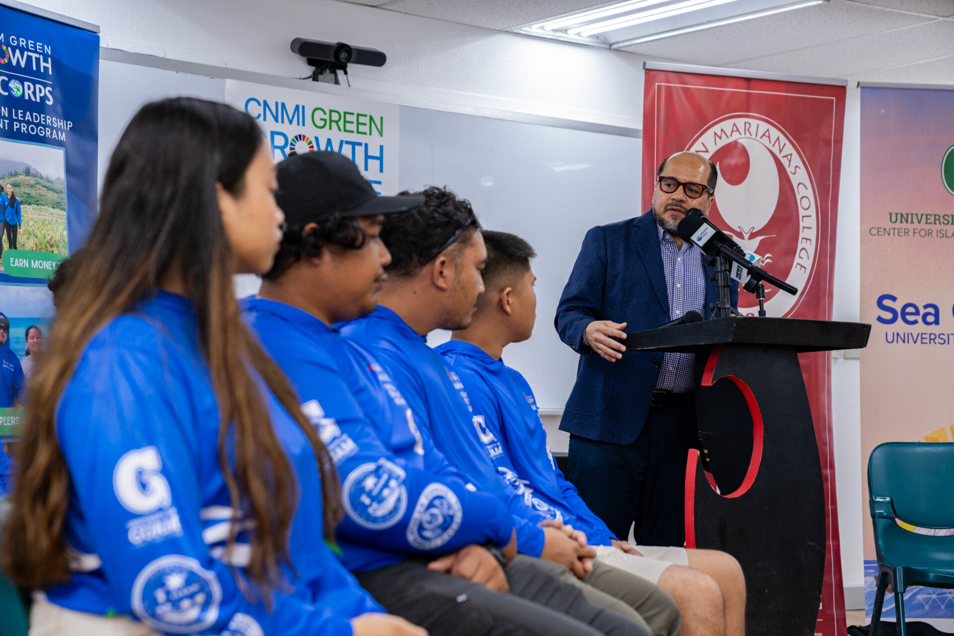 CNMI Green Growth Co-Chair Galvin De Leon Guerrero Ed.D. addresses the debut cohort of the CNMI Green Growth Kupu Conservation Corps during the launch event held on the NMC Campus.  The group features members who will be hosted by the American Memorial Park and DLNR CNMI Forestry learning skills and techniques to help them develop in the green economy.