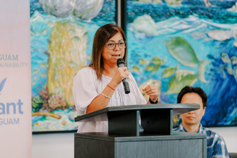 Fran Castro, UOG Sea Grant Associate Director, speaks into a microphone at a podium during a research funding announcement.