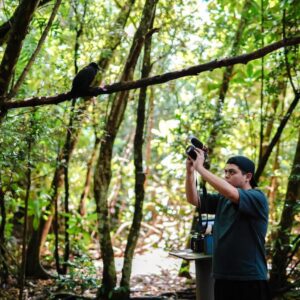 Thomas Manglona holds a camera up to take a photo while in the jungle.